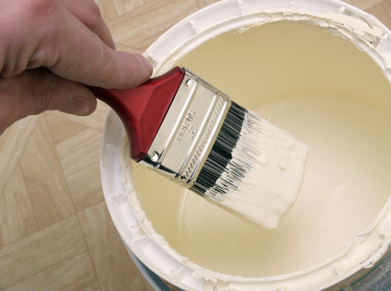 Paintbrush being dipped inside paint can